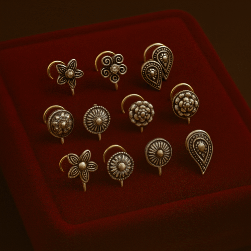 Set of 10 intricately designed antique-finish Rajasthani nose pins displayed on a red velvet box by H&A Jewellery.