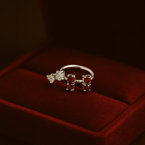 Elegant silver nose ring with sparkling white crystals and deep ruby-red stones by H&A Jewellery, displayed on a red velvet box.